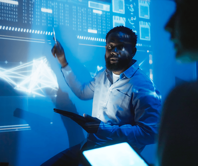 Man Illuminated by Smartboard and Pointing at Data