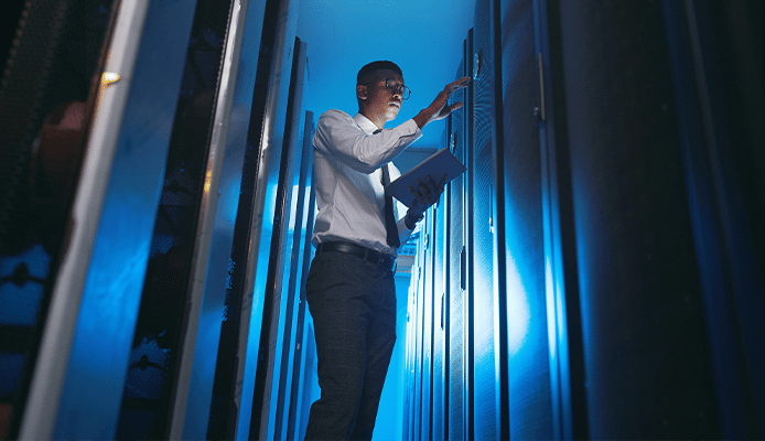 Man in a Dark Server Room Using a Tablet
