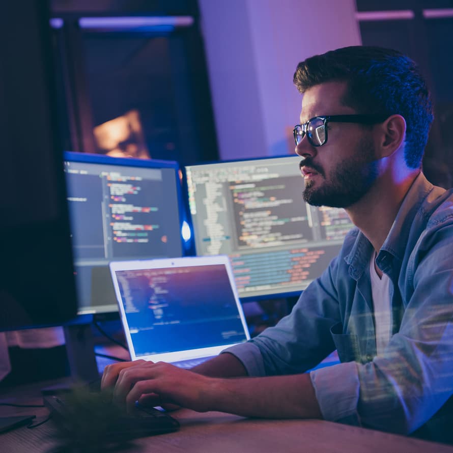 Man Surrounded by Computers in Dark Room