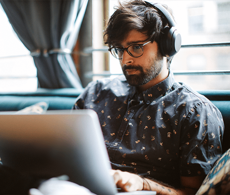 Man with Headphones Looking at Laptop