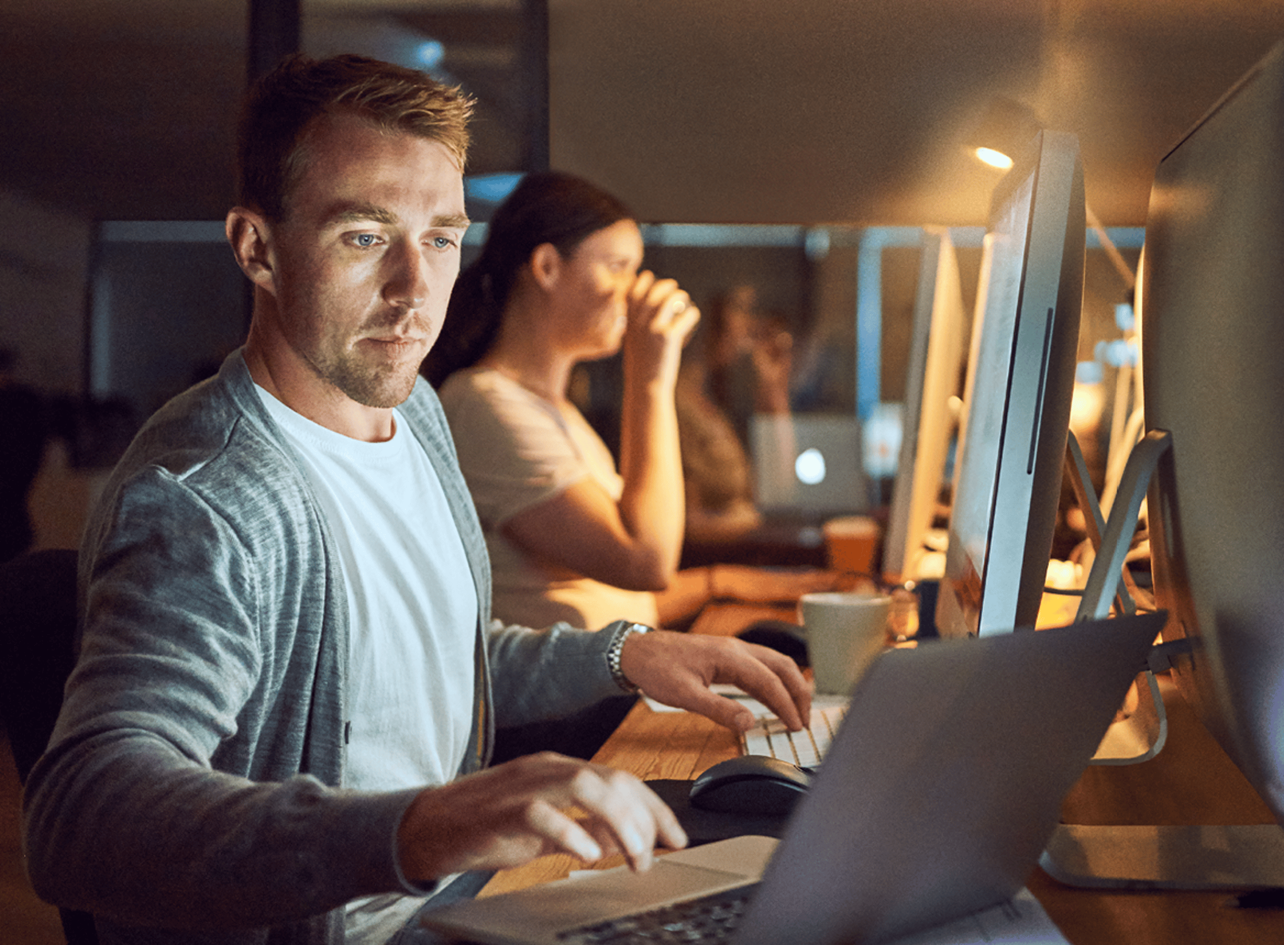 Man Typing at Shared Desk in Office