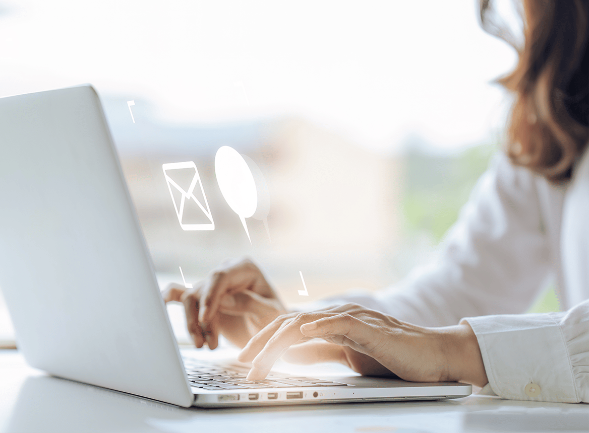 Person Typing on Laptop with Communication Icons Floating Above the Hands
