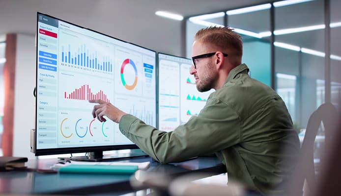 Man Pointing at Big Computer Monitors