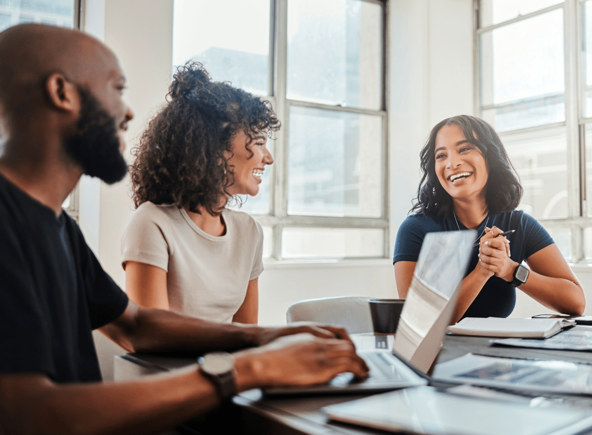 Three people smiling during a meeting in an office