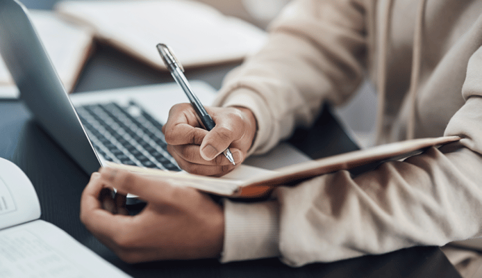 Close Up of Woman Taking Notes in a Notebook