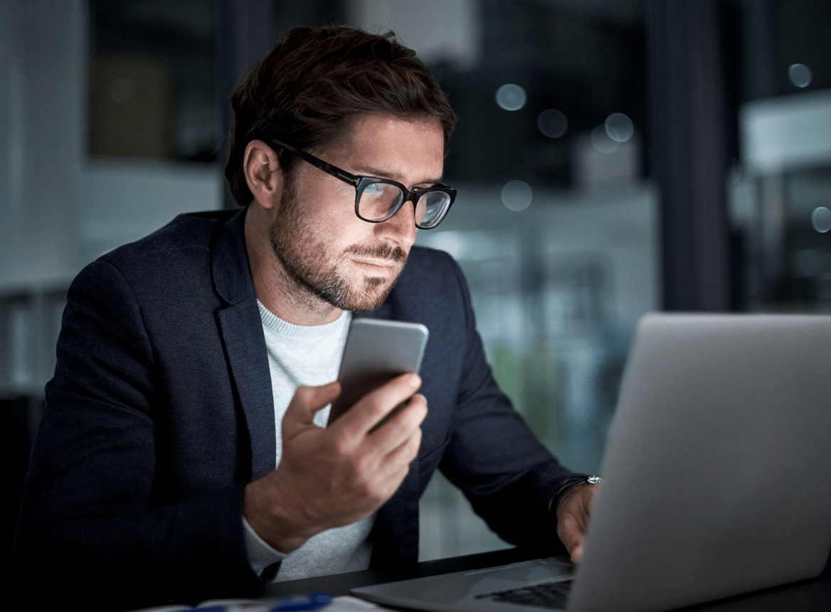 Man Using Laptop and Phone