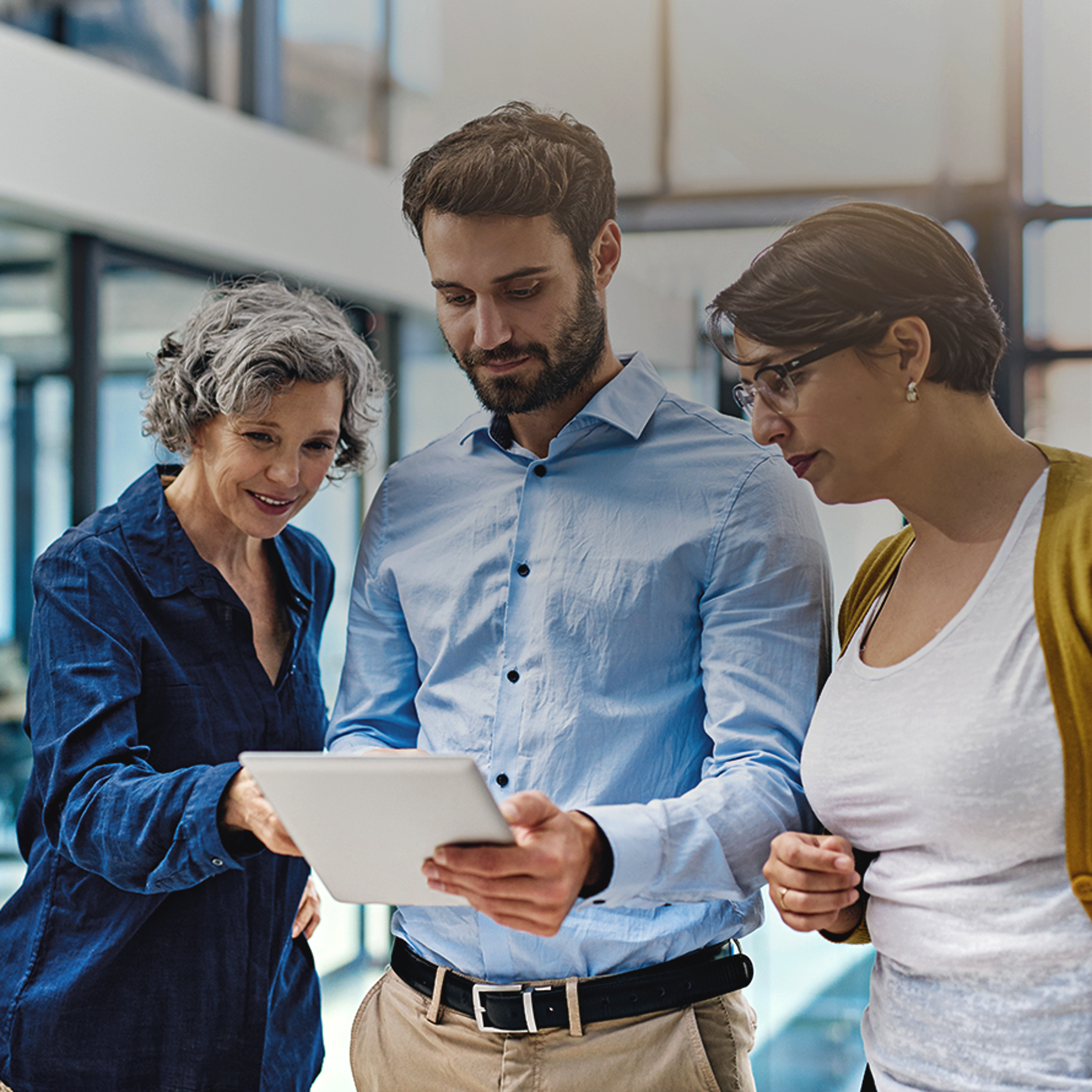 Three People In an Office Looking at a Tablet