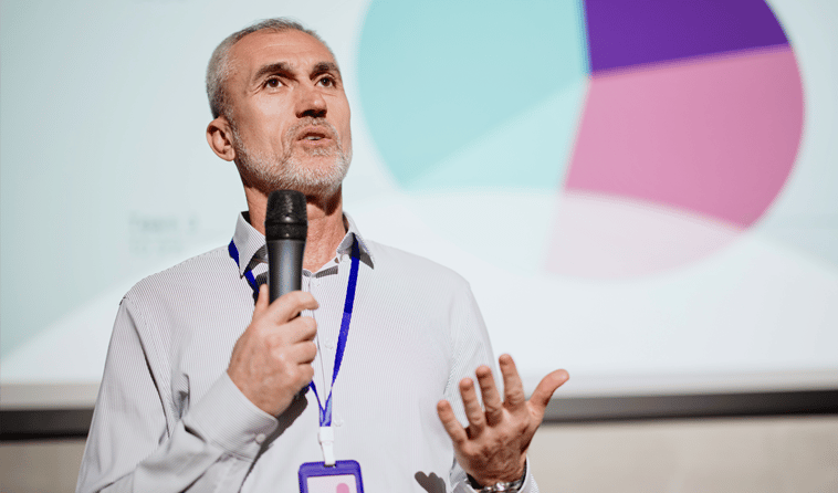 Close Up of Man Speaking into Microphone on a Stage