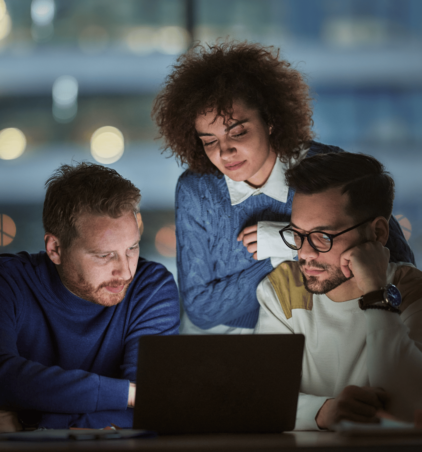 Three People Gathered Around a Laptop in Business Setting