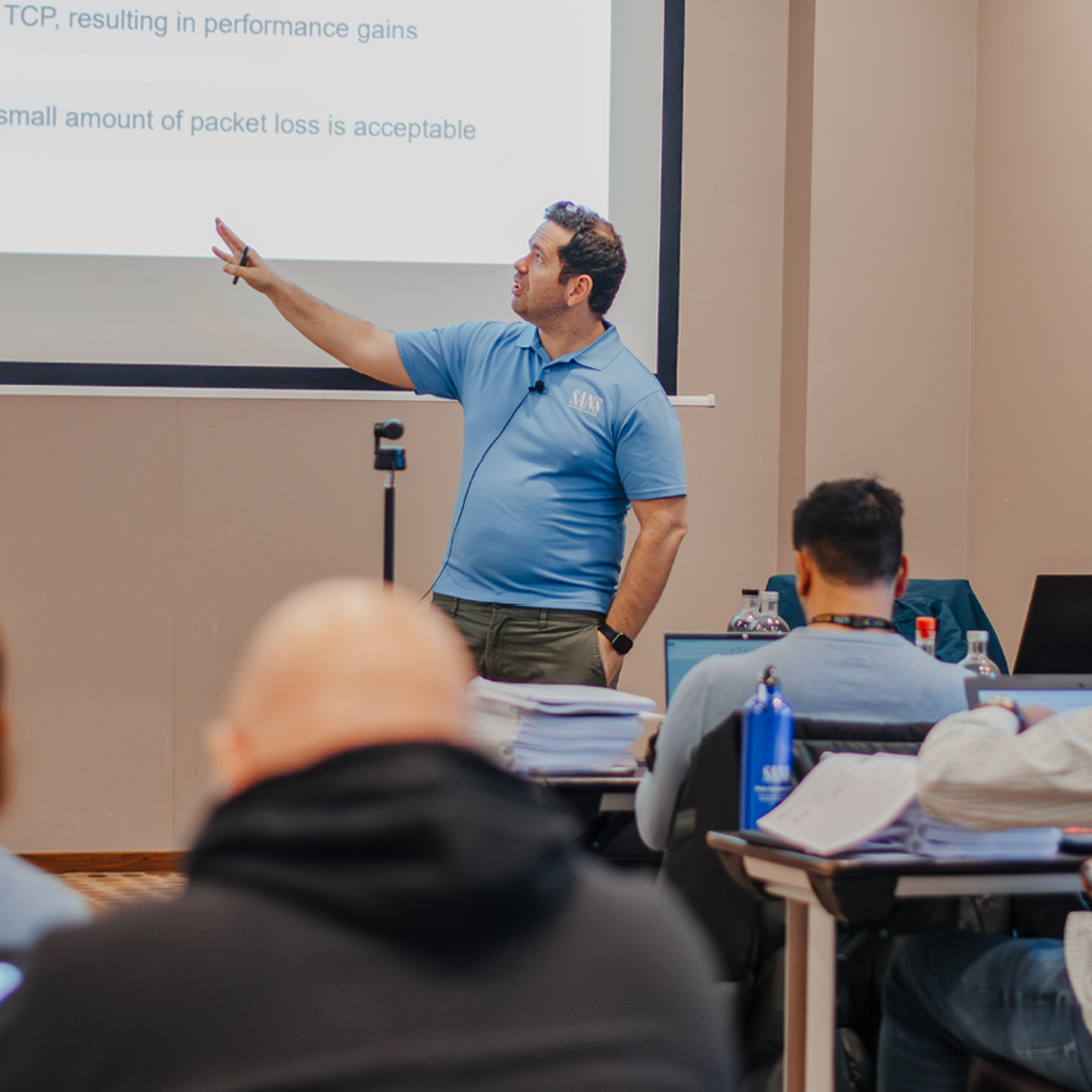 Teacher in Blue Shirt Explaining Material On Large Screen