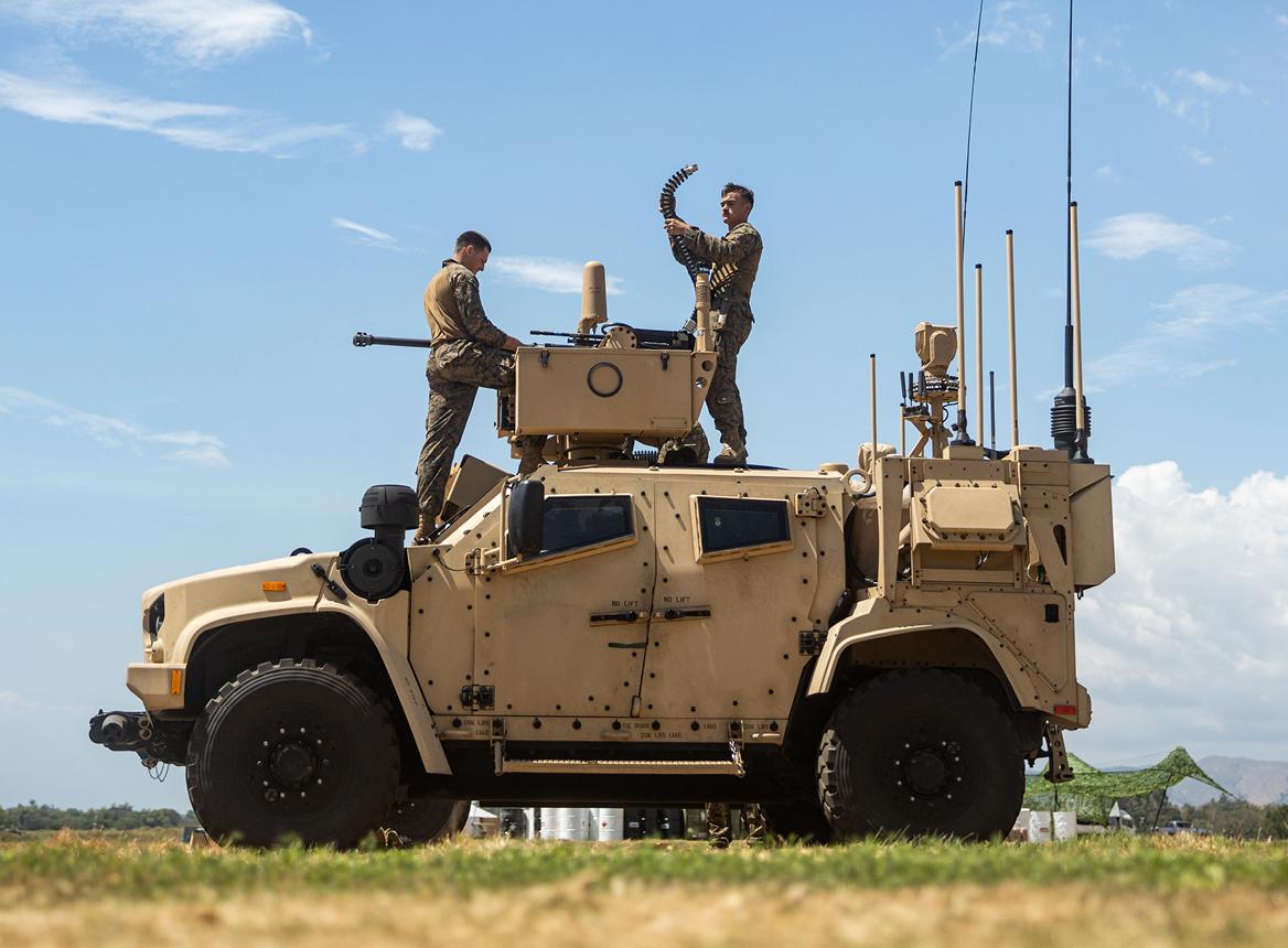 Two Soldiers On Top of Military Vehicle in Desert Gear