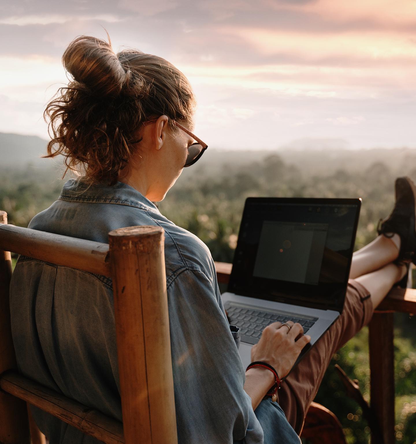 Woman With Her Feet on Railing and Laptop on Her Lap