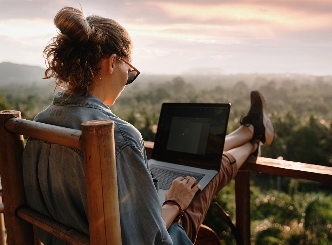 Woman With Her Feet on Railing and Laptop on Her Lap