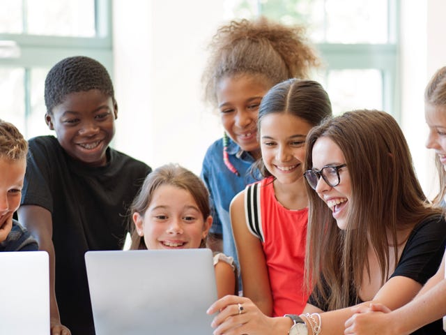 Group of diverse school children smiling and learning on laptops during a language class