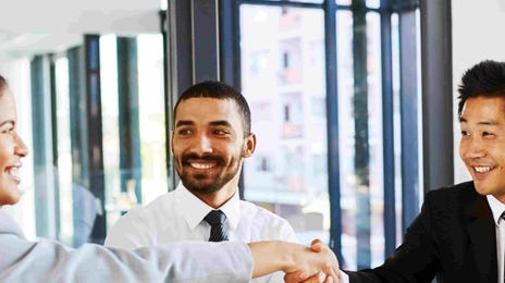 Business professionals shaking hands during a successful Berlitz corporate English training session in a modern office environment.