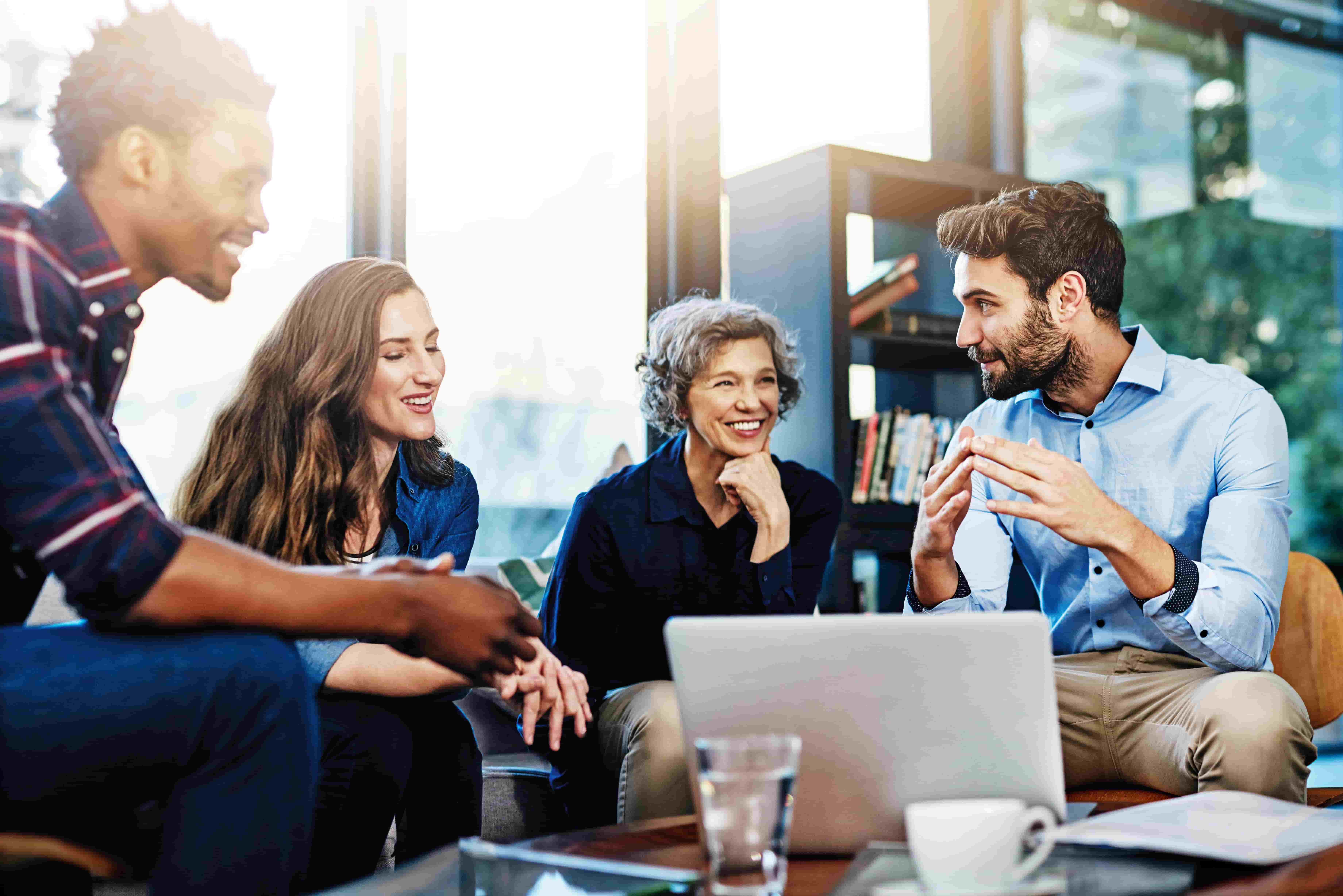 Group of professionals engaged in a collaborative discussion around a laptop.








