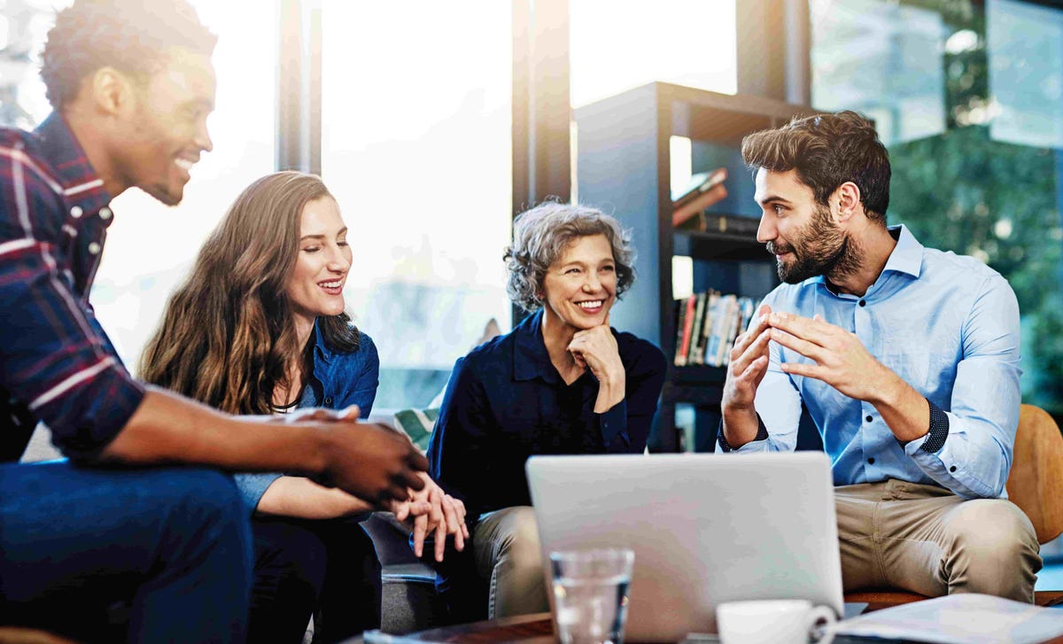 Group of professionals engaged in a collaborative discussion around a laptop.