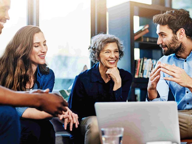 Group of professionals engaged in a collaborative discussion around a laptop.