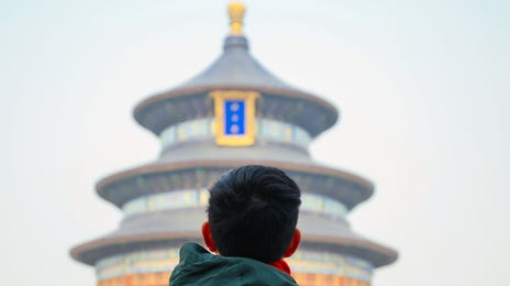 A young traveler with a backpack faces the Temple of Heaven in Beijing, symbolizing cultural immersion and the opportunity to learn Mandarin online.