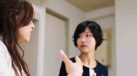 Two women engaged in a focused conversation during a Japanese language class, emphasizing interactive learning in Berlitz’s teaching method.