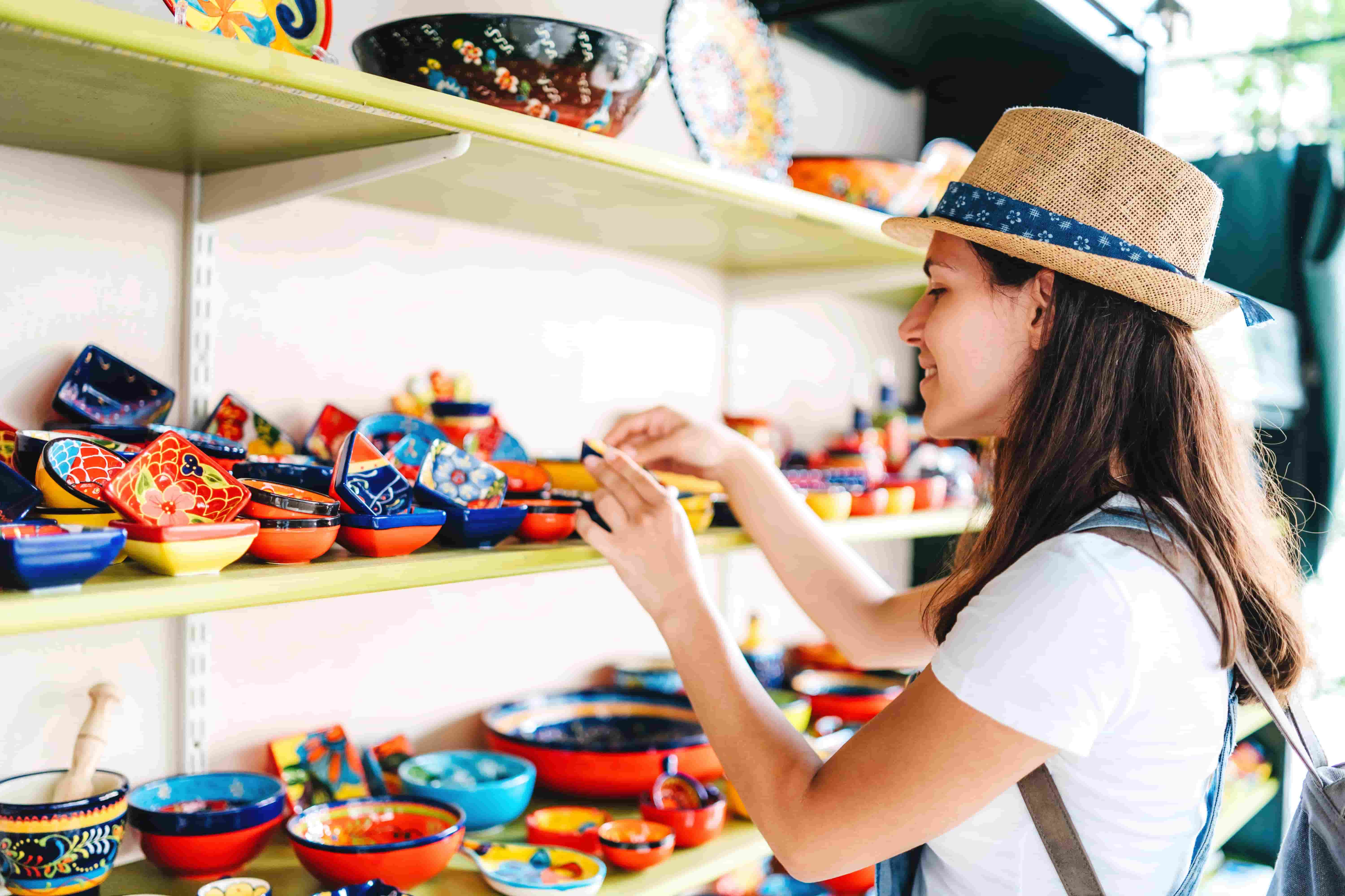 Smiling woman browsing colorful handmade ceramics, capturing the cultural immersion aspect of Berlitz Spanish courses.


