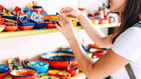 Smiling woman browsing colorful handmade ceramics, capturing the cultural immersion aspect of Berlitz Spanish courses.