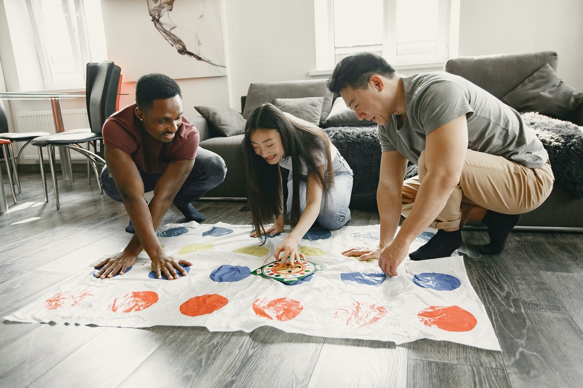 Friends playing twister to learn the body parts in Italian.