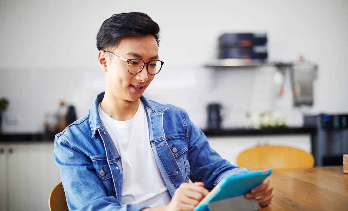 Young man taking an English level test on a tablet in a modern kitchen workspace.