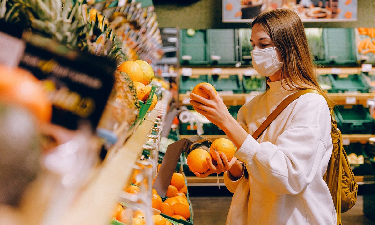 Young woman shops for fruit in English.