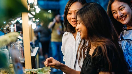 Group of women enjoying Thai street food at night, reflecting cultural immersion tied to Thai lessons and language learning experiences.