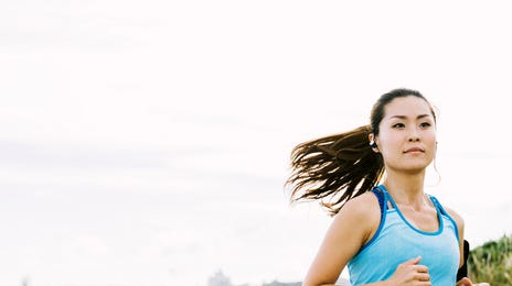 Woman jogging outdoors while listening to an audio lesson from advanced English courses