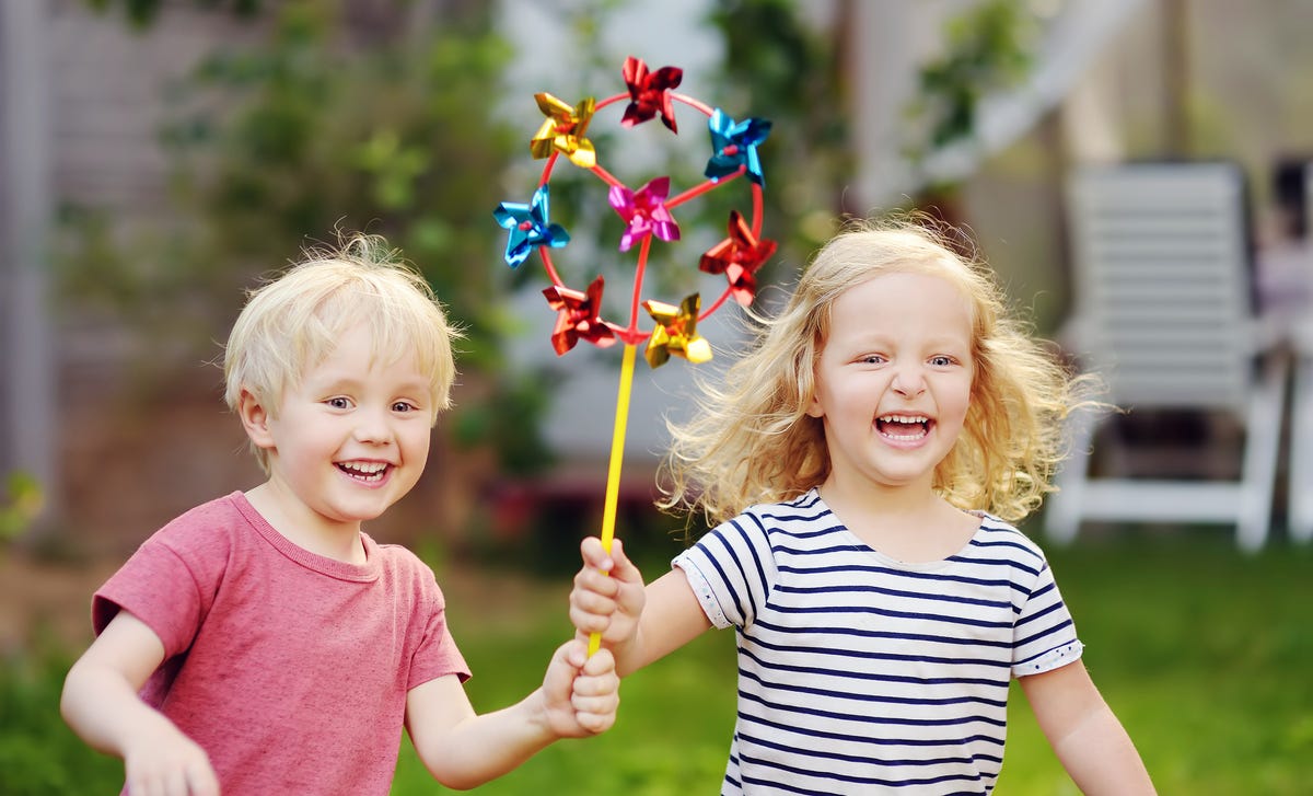 Happy young children playing with a colorful pinwheel outdoors, symbolizing fun and engaging French language learning for kids