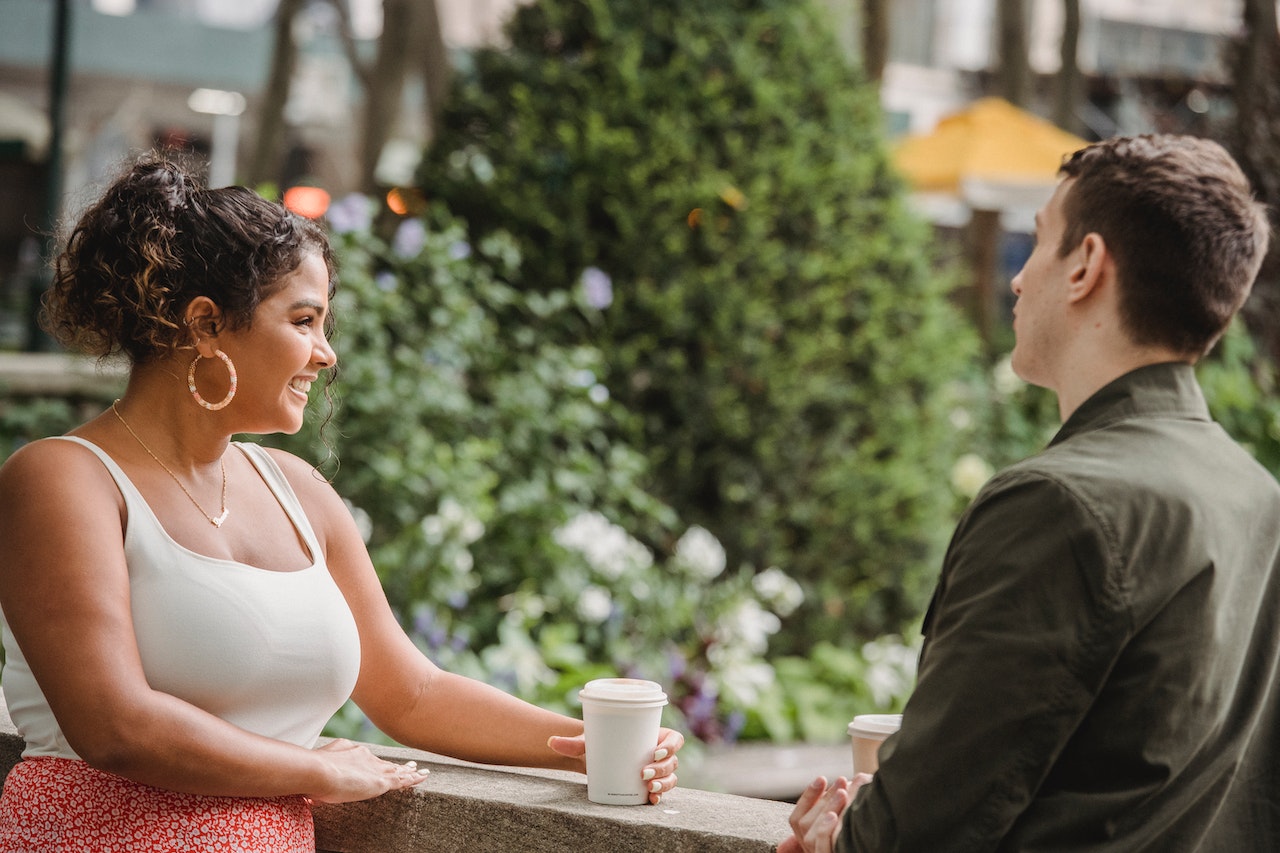 A diverse man and woman are having coffee on a date, after he tested German pick up lines on her.