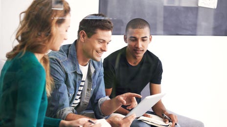 Diverse group of young adults learning Romanian together with digital tablets and notes in a casual setting