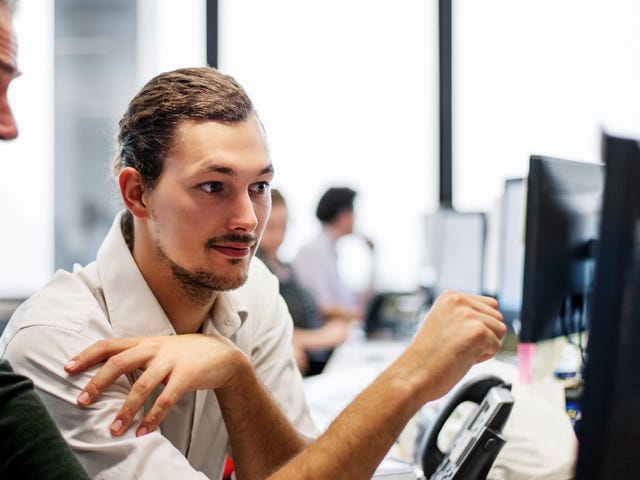 Two professionals reviewing Berlitz language proficiency test results on a computer in a modern office