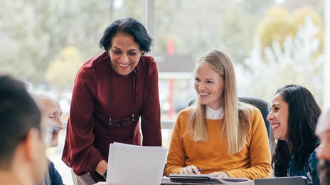 Diverse group of professionals engaging in discussion and document review during a business English course session