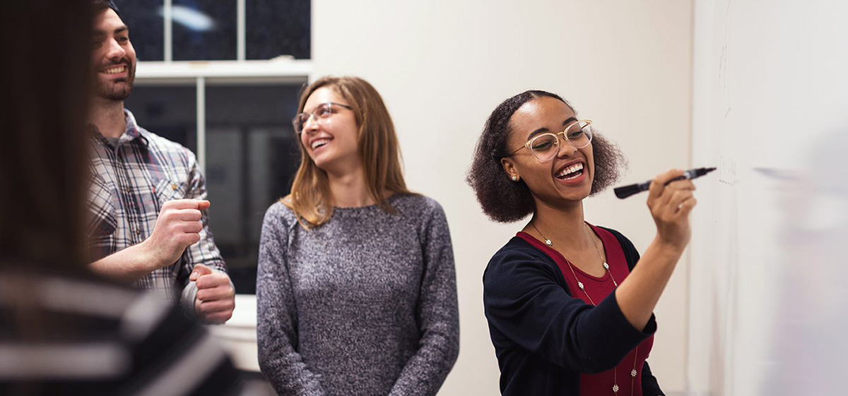 Group of friends learning English pronouns on a classroom whiteboard