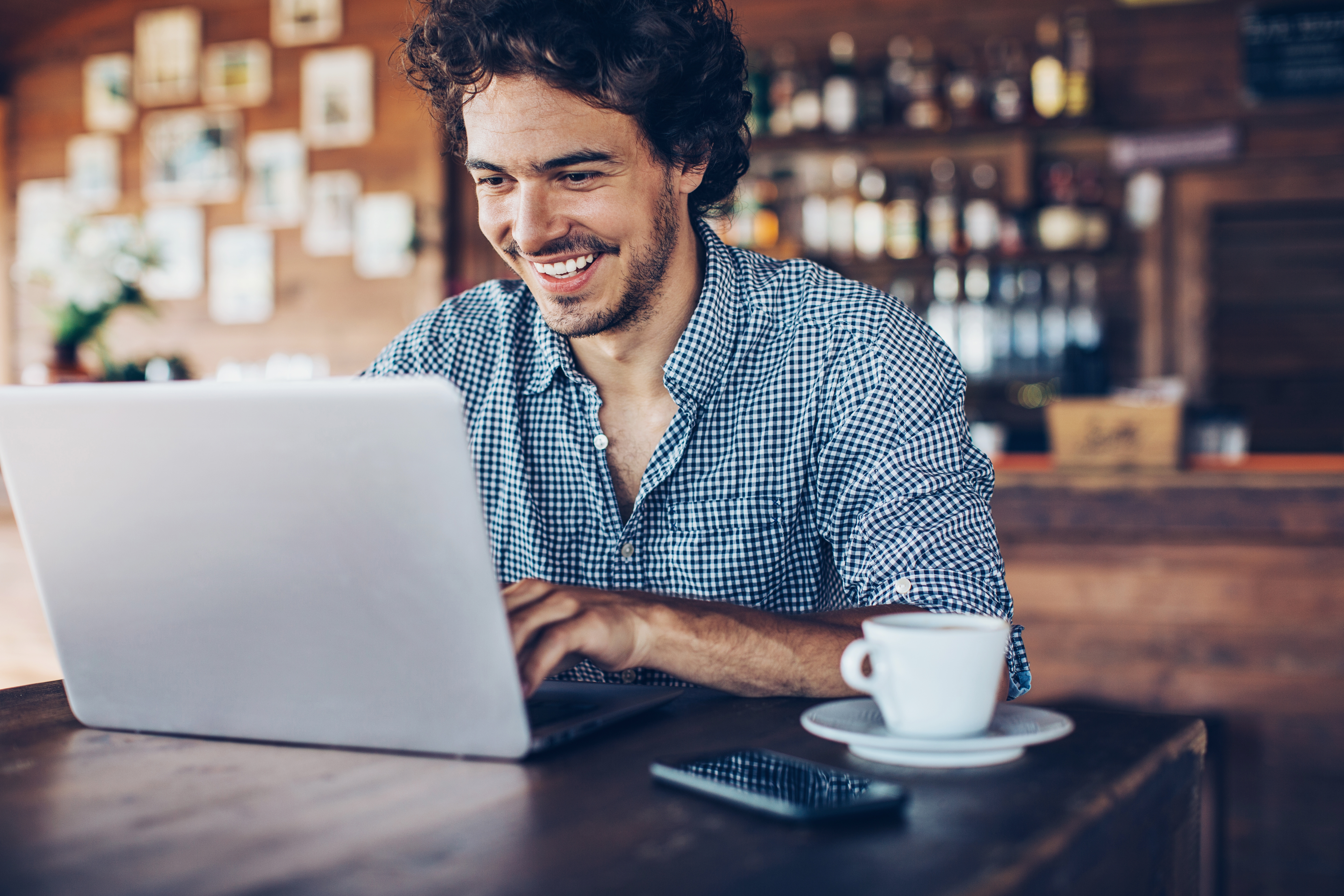 Man smiling while attending online Portuguese group class from a café