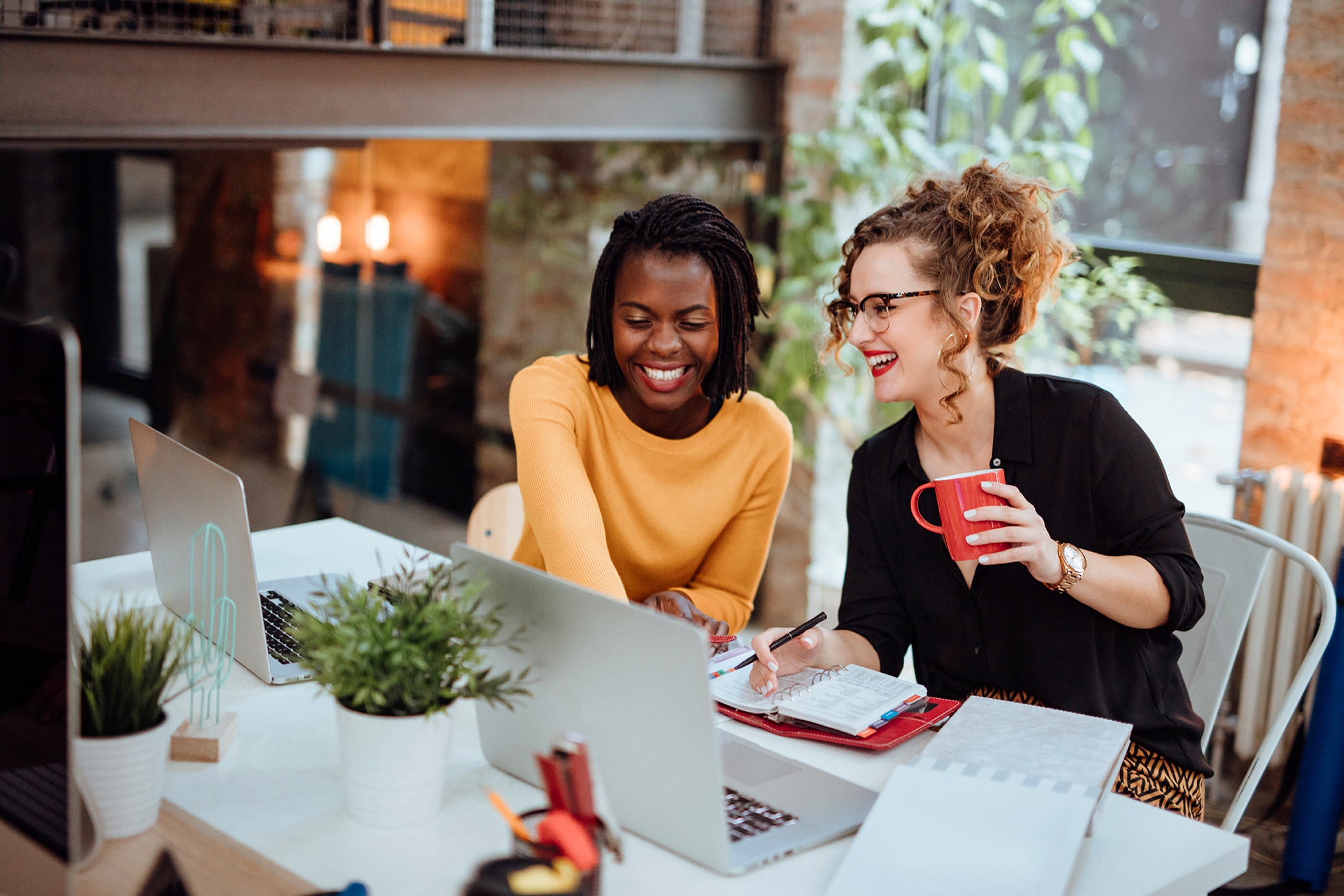 Two women collaborating in a modern office, capturing the dynamic and supportive work culture promoted through Berlitz careers.

