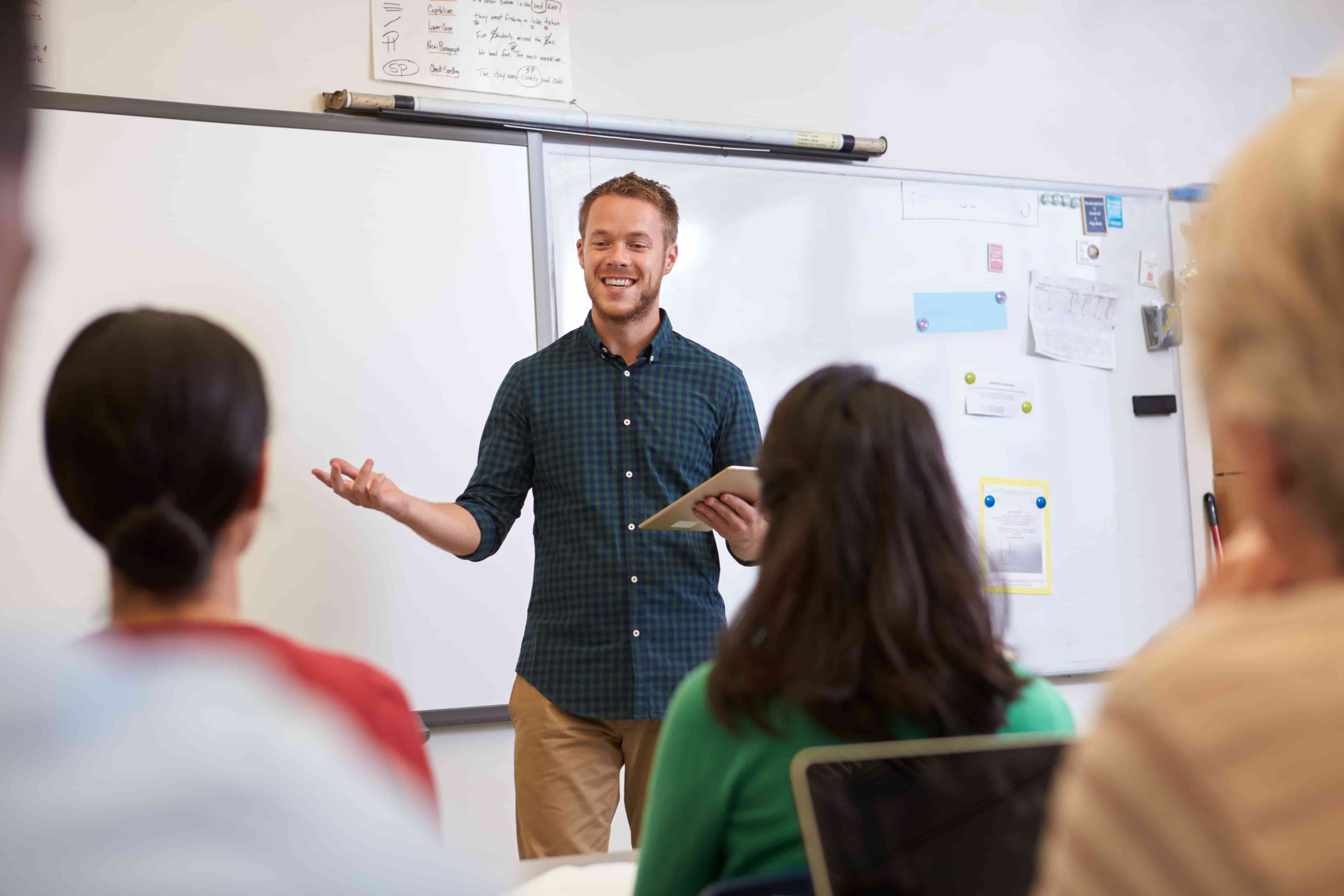 Language instructor smiling and engaging adult students in a Berlitz classroom setting, highlighting a professional language school environment.







