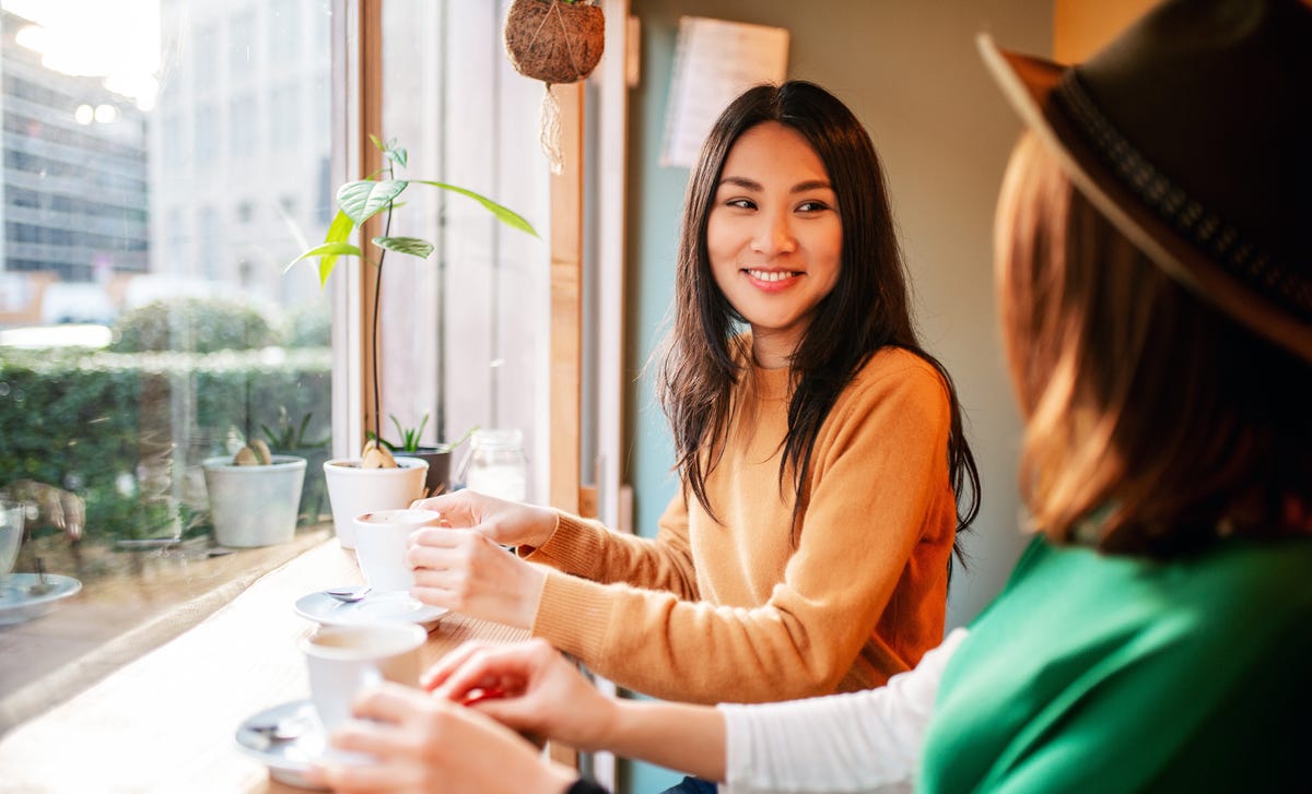 Two women practicing conversation skills at a café, illustrating Berlitz language school’s focus on real-life communication.