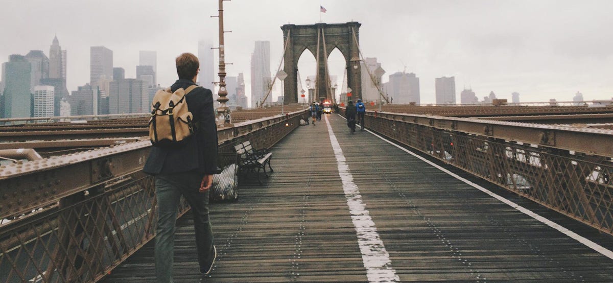 Man walks over the Brooklyn Bridge.