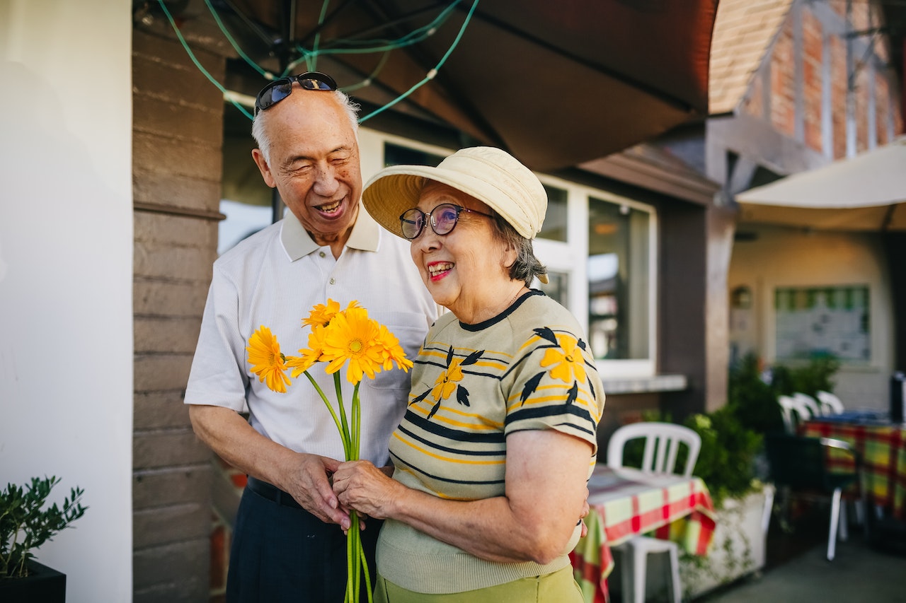 Cute elderly couple holding bouquet of flowers smiling at their grandma and grandpa nicknames in French.
