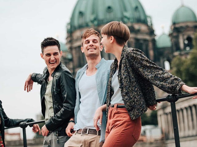 Group of young adults smiling and chatting outside a historic building in Berlin, symbolizing the cultural immersion offered by Berlitz language school programs.