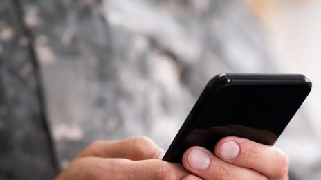 A military officer using a smartphone, symbolizing the importance of government translation services for communication and operations.