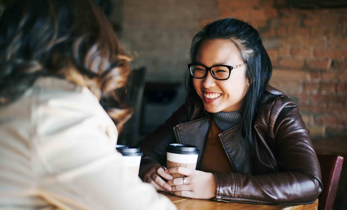 Two women enjoying coffee and conversation, symbolizing the friendly and engaging work culture offered by Berlitz careers.