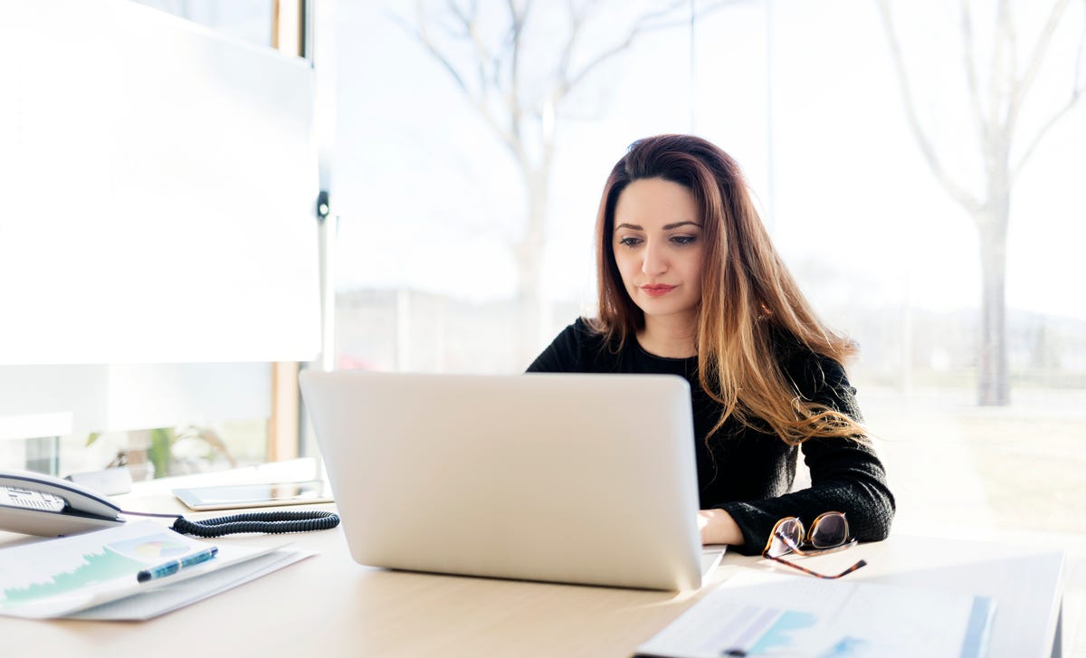 A woman studying at her desk with a laptop, representing learning Hindi online in a bright and modern workspace.