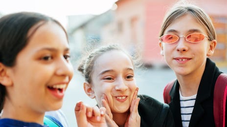 Group of smiling school-age kids taking a fun selfie after French class, showing excitement and friendship