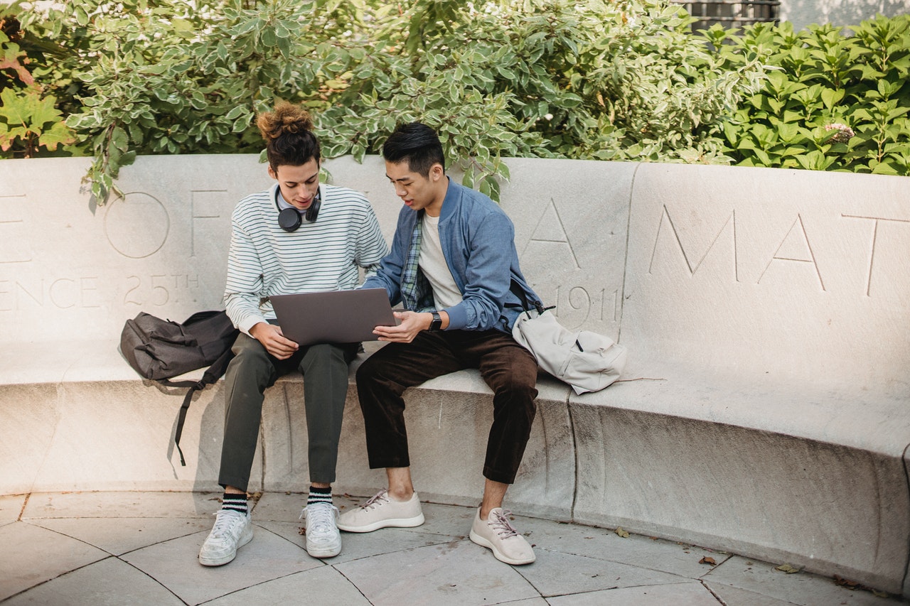 Two male colleagues sitting in a park as an example of workplace mentoring