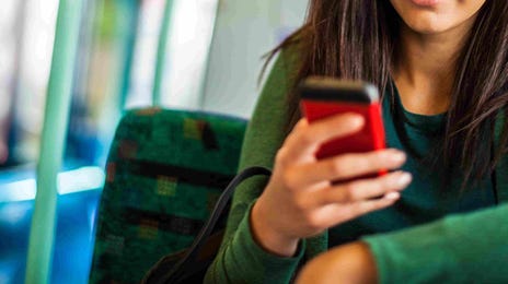 Young woman on a bus using her phone, focused and engaged.